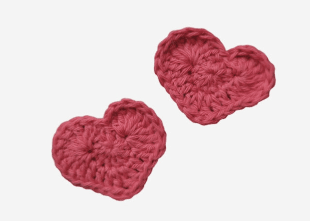 Two small, textured pink crocheted hearts are displayed on a white background.
